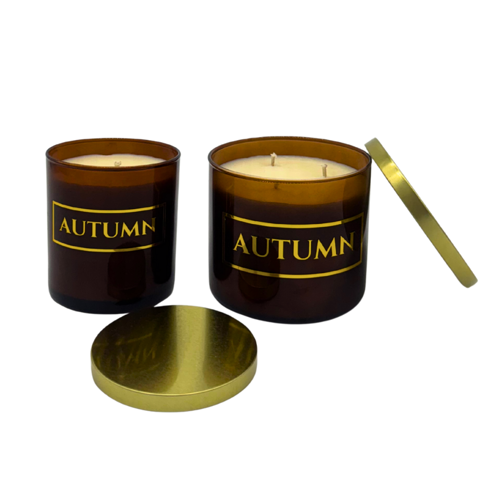 Two 'AUTUMN' scented candles with gold lids on a white background