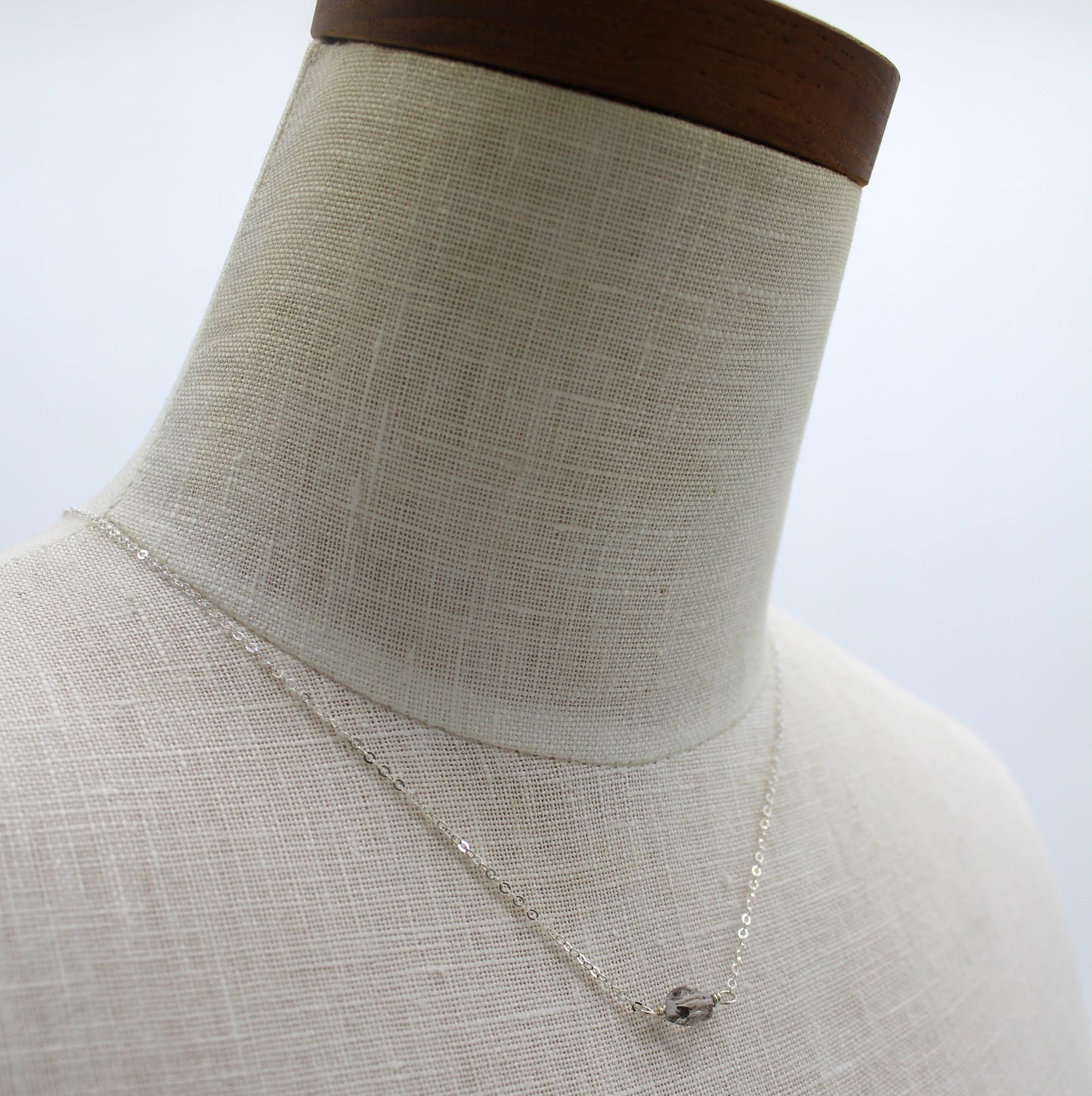 A dainty beautiful silver chain featuring a faceted Herkimer diamond in the center.