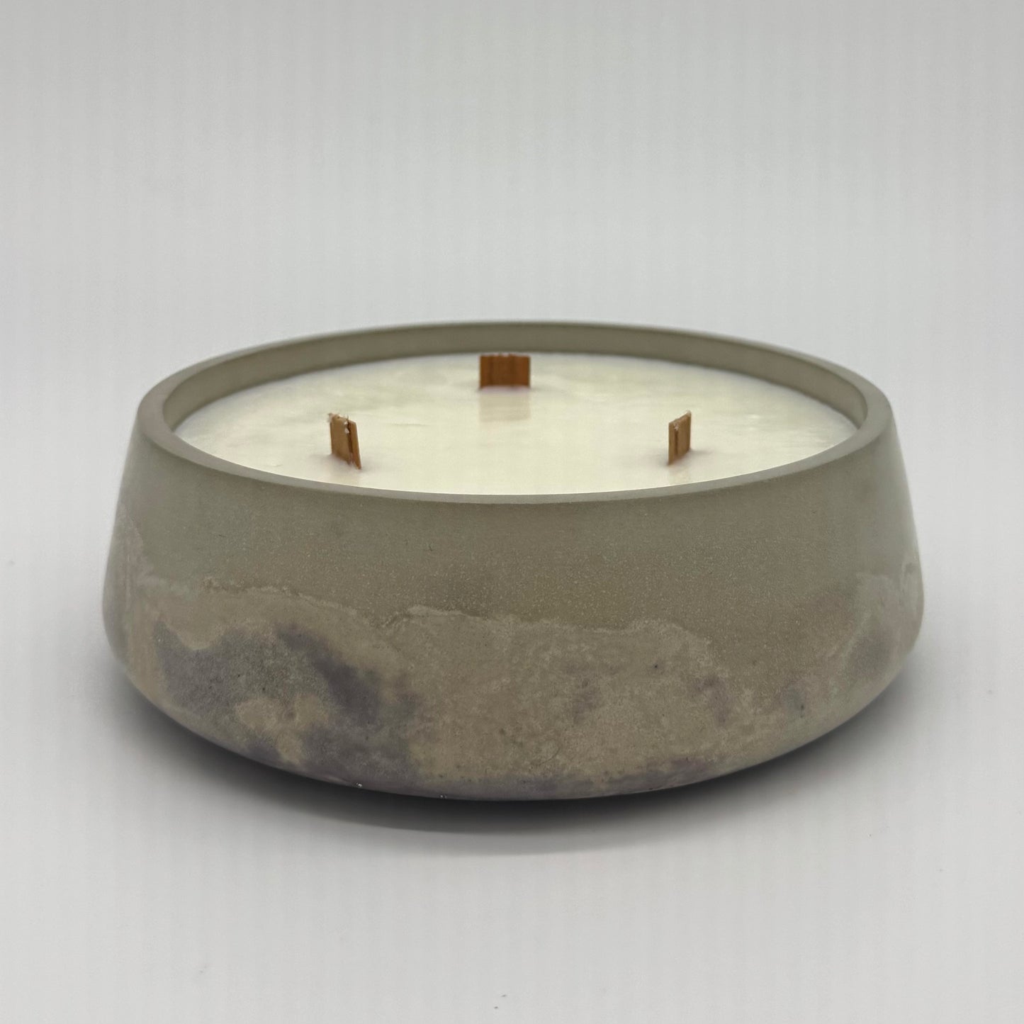 Concrete candle holder with a white candle inside on a light gray background