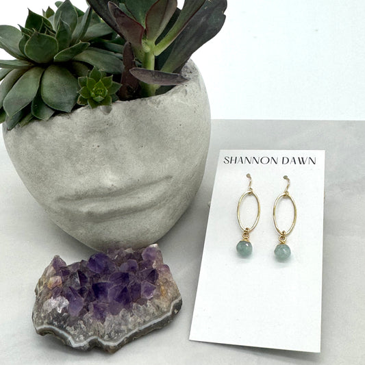Earrings on a card with a plant and amethyst crystal