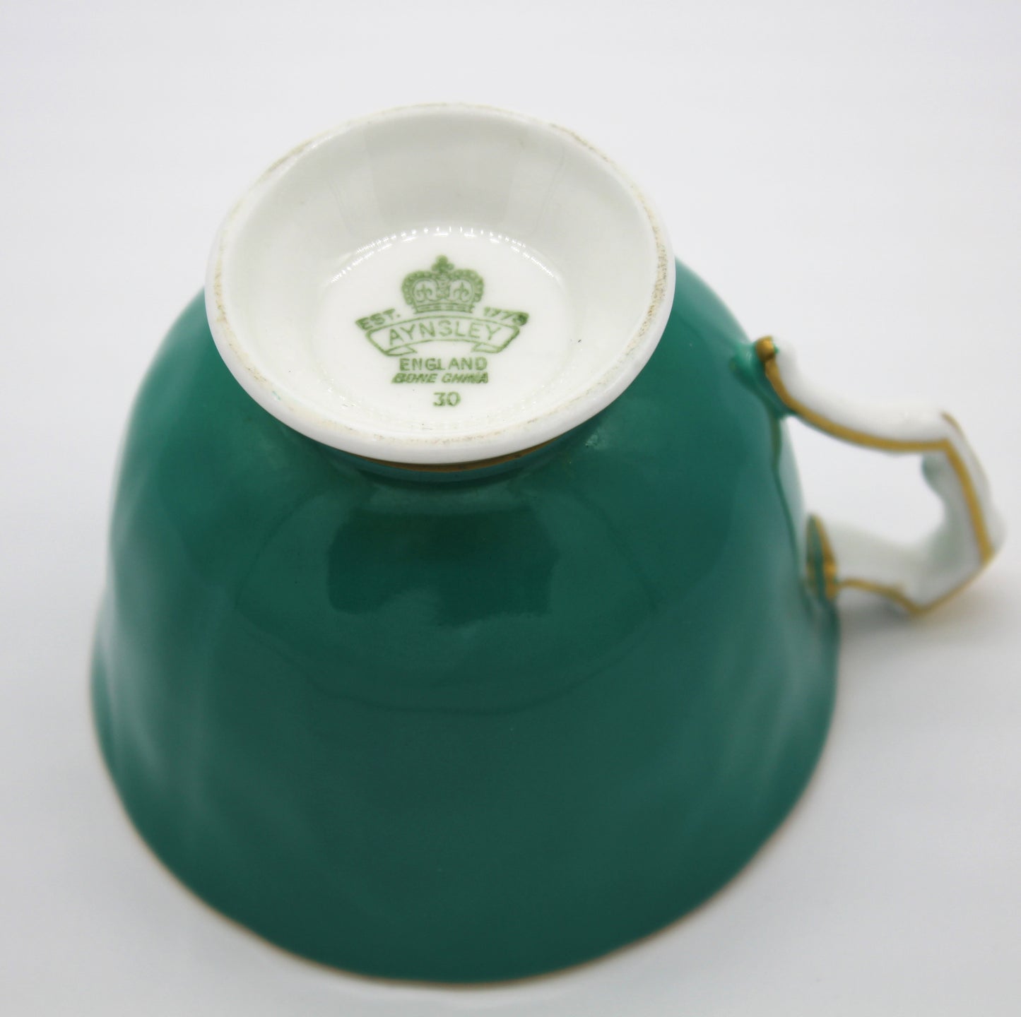 Teal teacup with a white interior on a light gray background