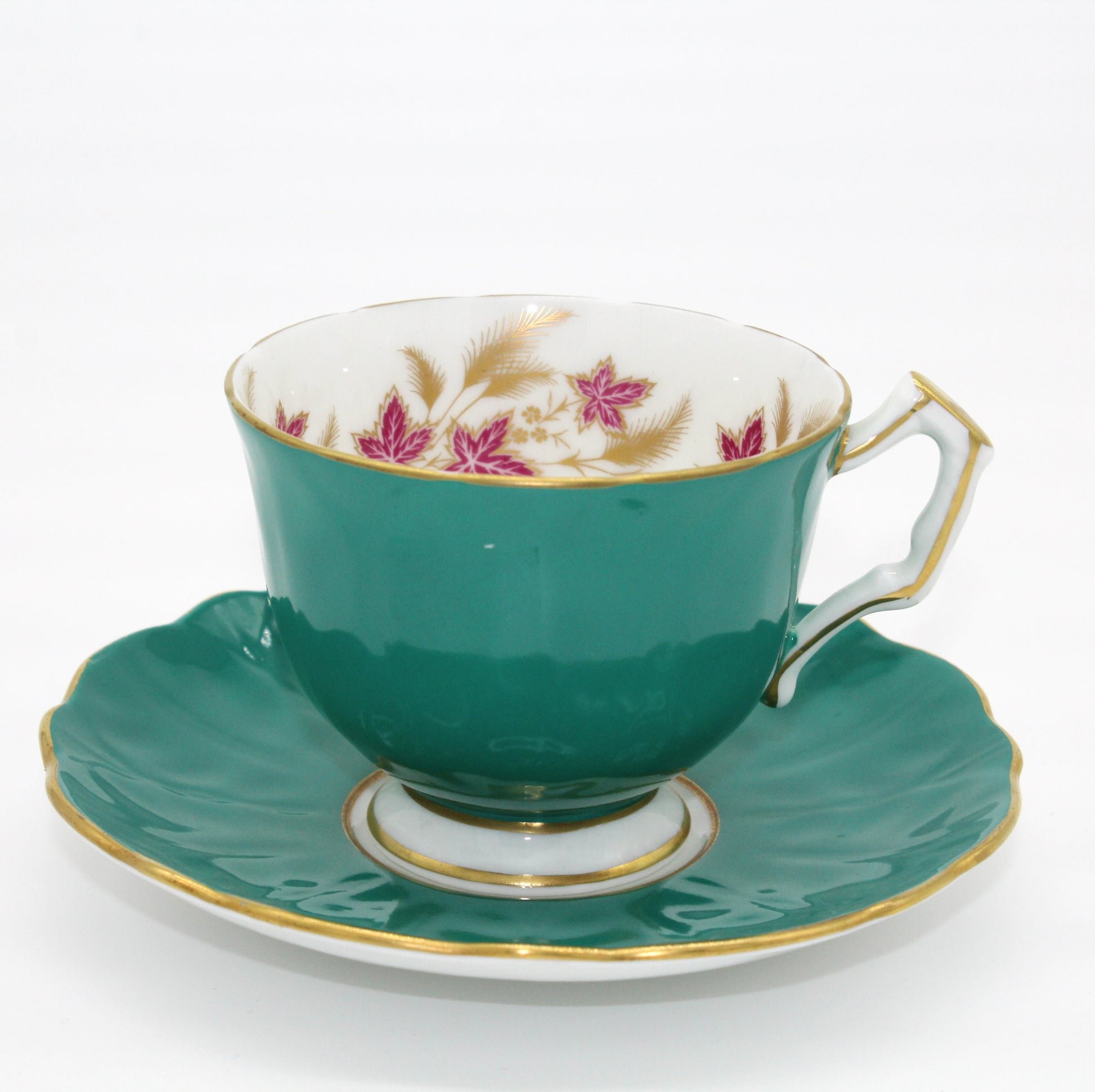 Teal teacup and saucer with floral patterns on a white background