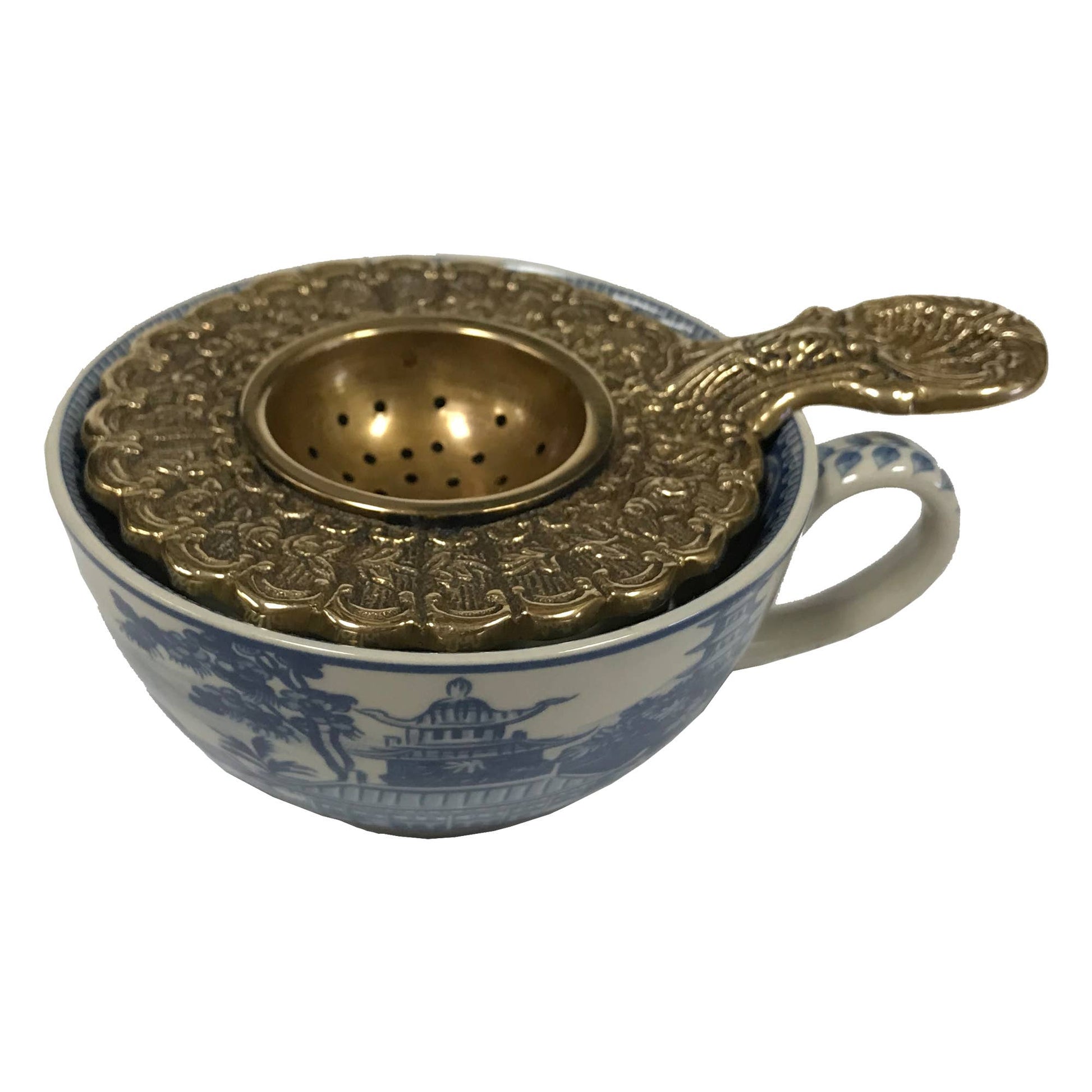 Brass Decorative Tea Strainer in teacup on white background.