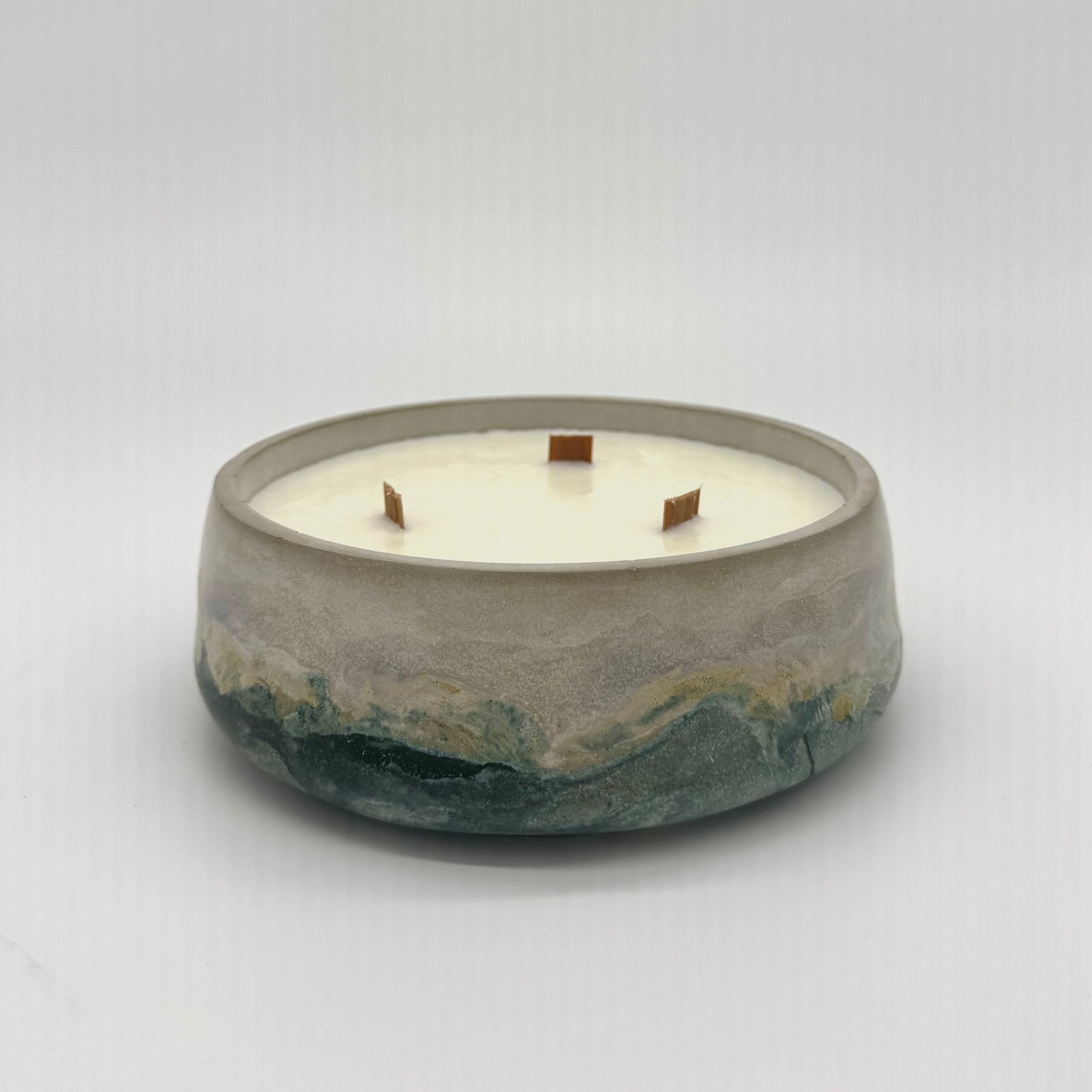 Concrete candle with a white candle and three wood wicks on a light gray background