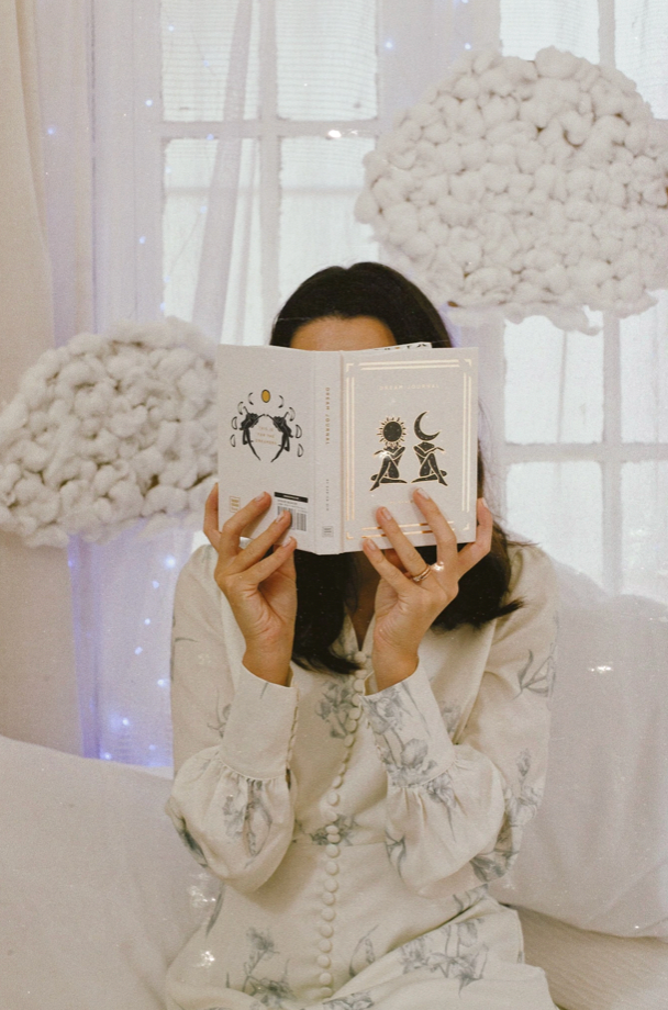 Person holding a book with decorative elements in a softly lit room.