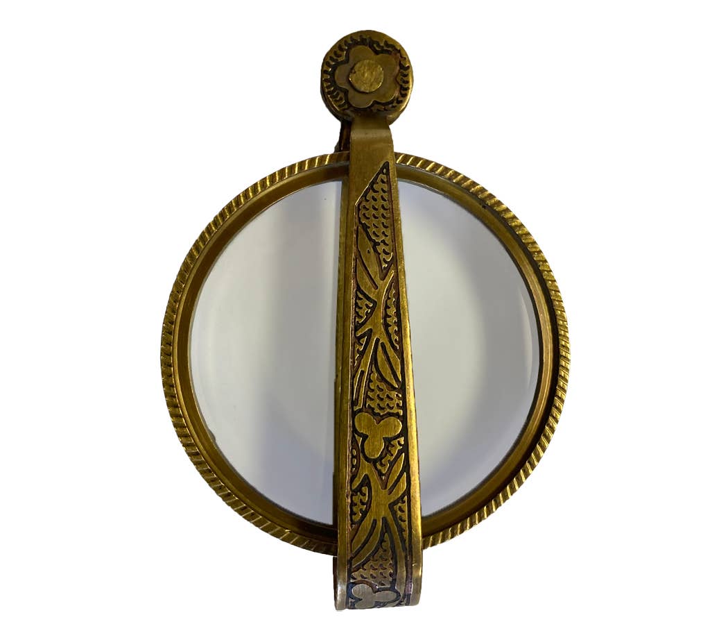 Decorative brass mirror with intricate designs on a white background