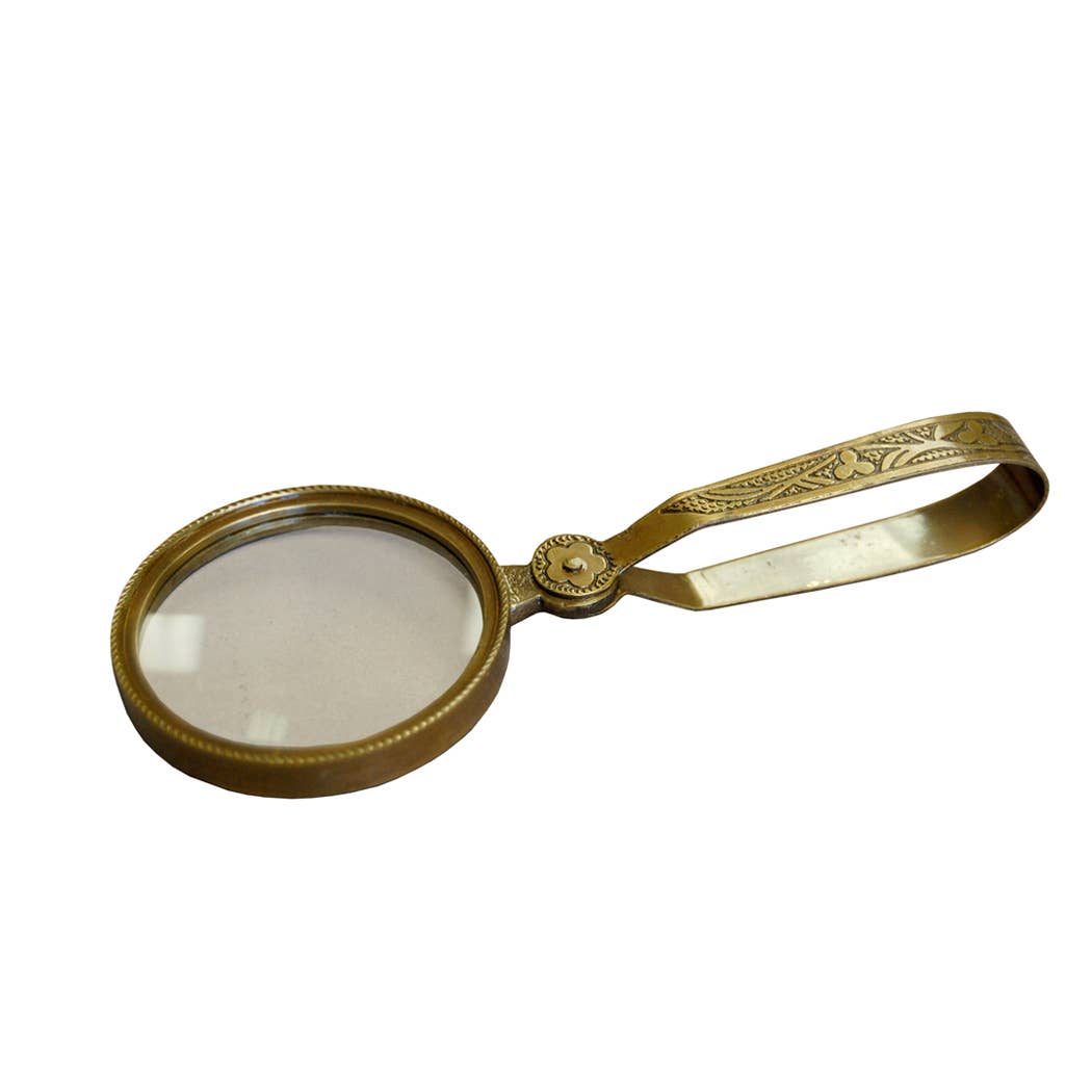 Gold magnifying glass with decorative handle on a white background