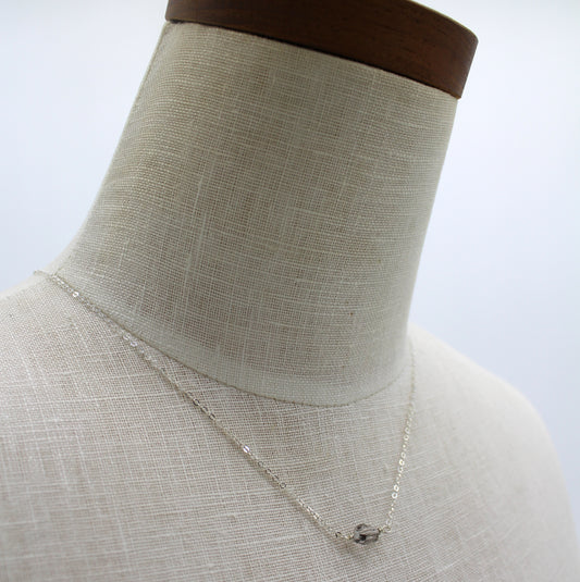 A dainty beautiful silver chain featuring a faceted Herkimer diamond in the center.