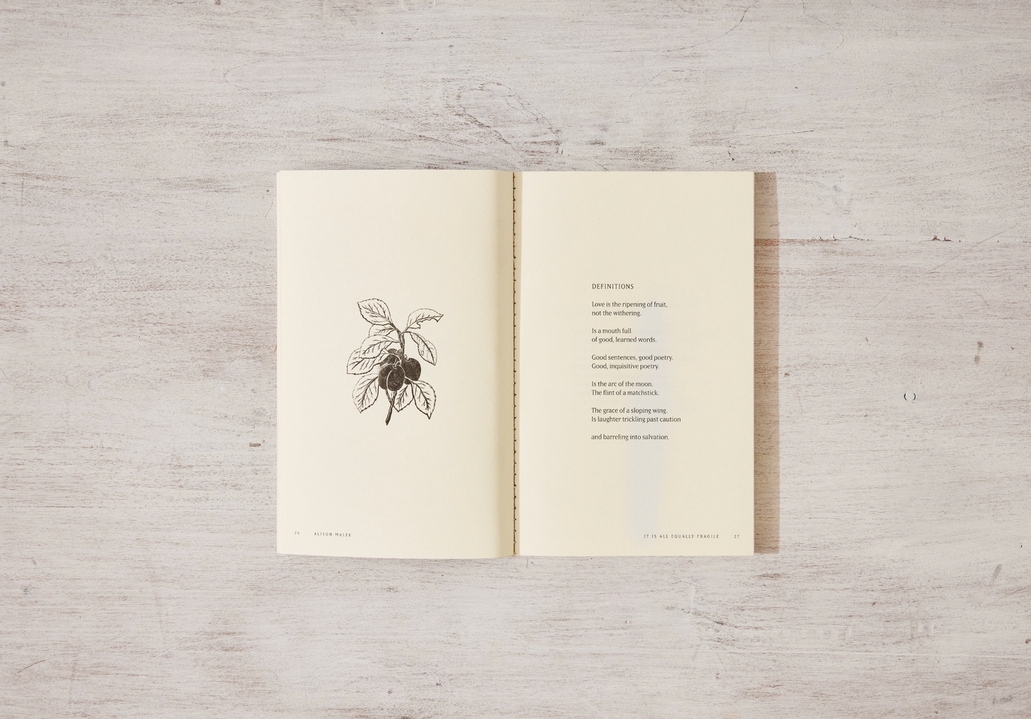 Open book with a drawing of olives on a wooden surface