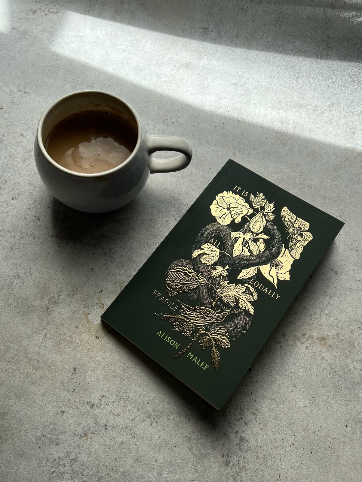 Book with floral design and a cup of coffee on a concrete surface