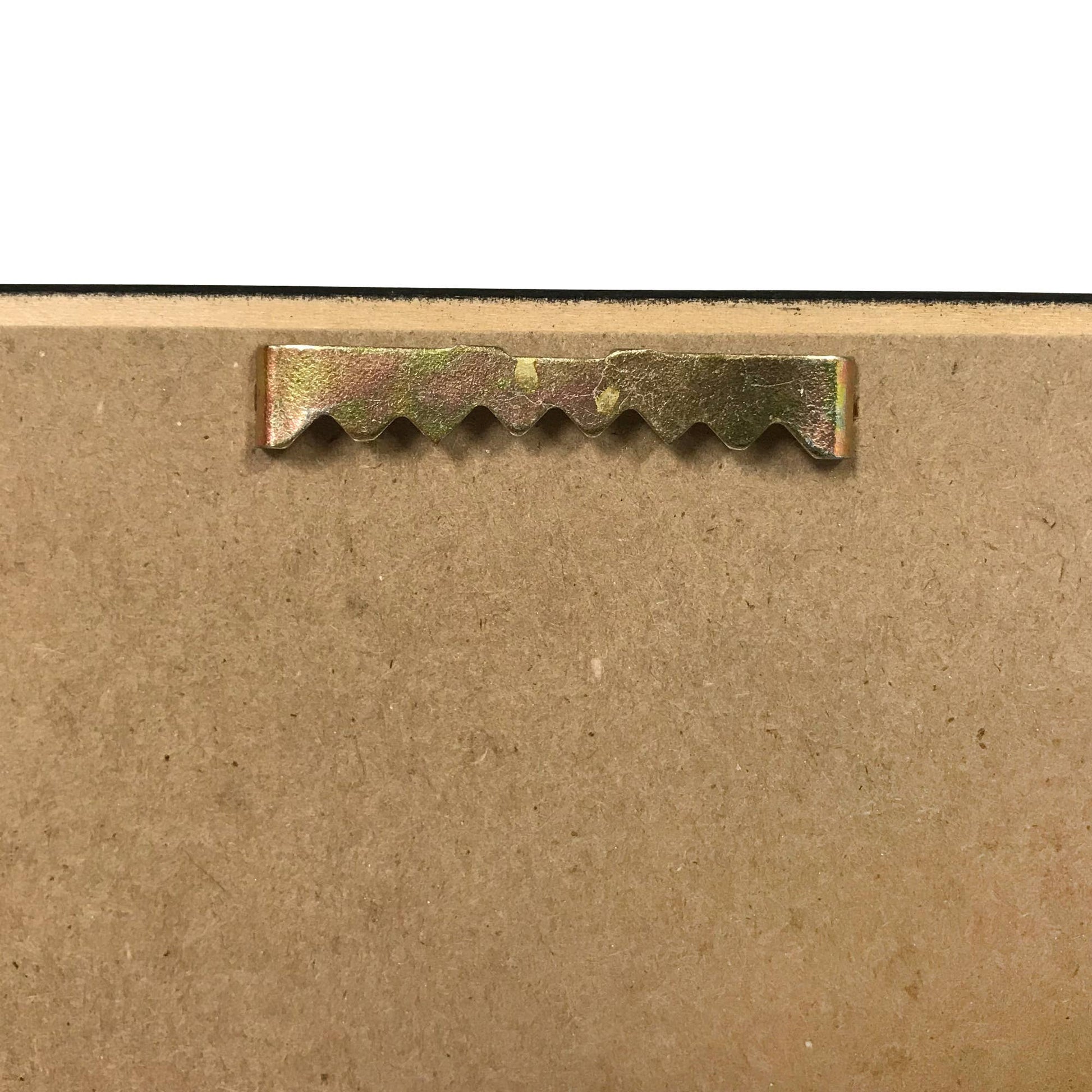 Close-up of a metal strip with teeth on a cardboard background