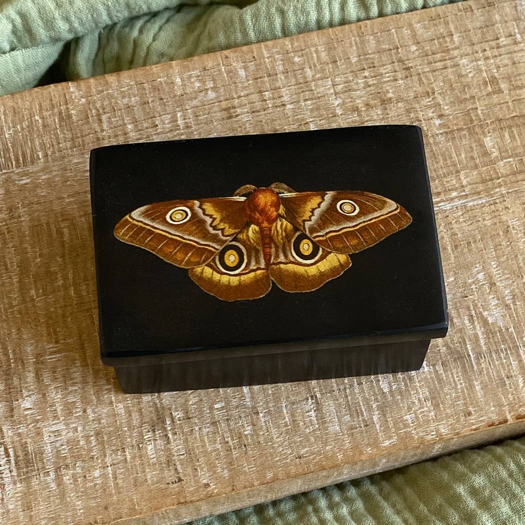 Wooden box with a moth design on a wooden surface
