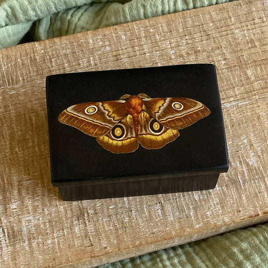 Wooden box with a moth design on a wooden surface
