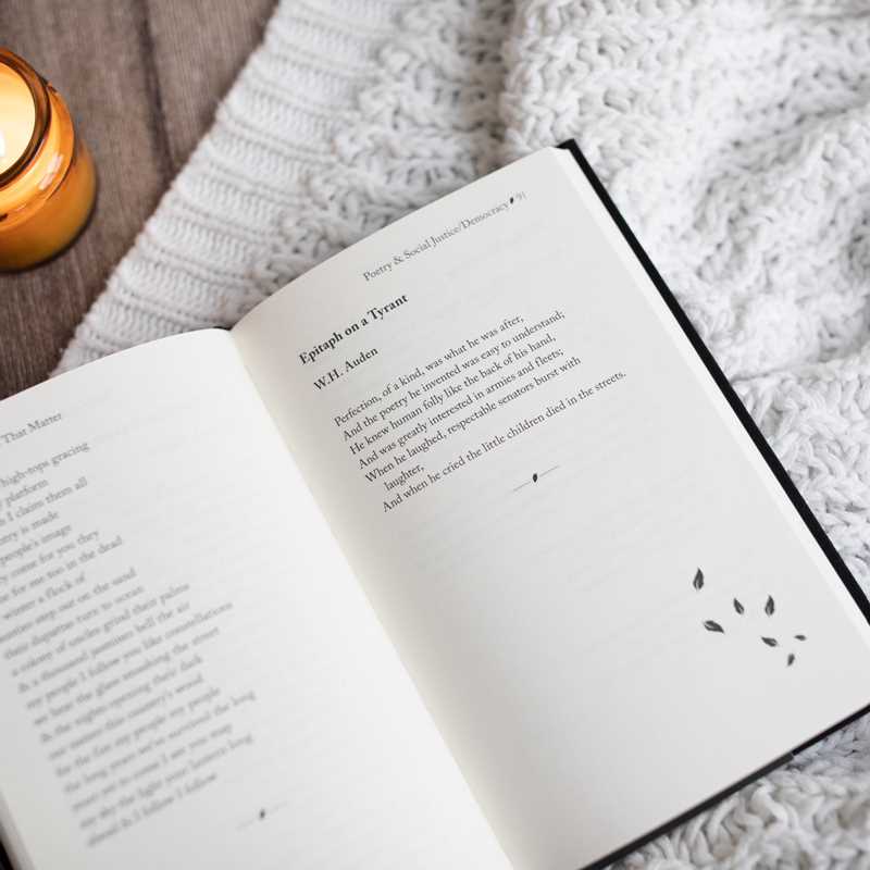 Open book with text on a textured surface next to a candle