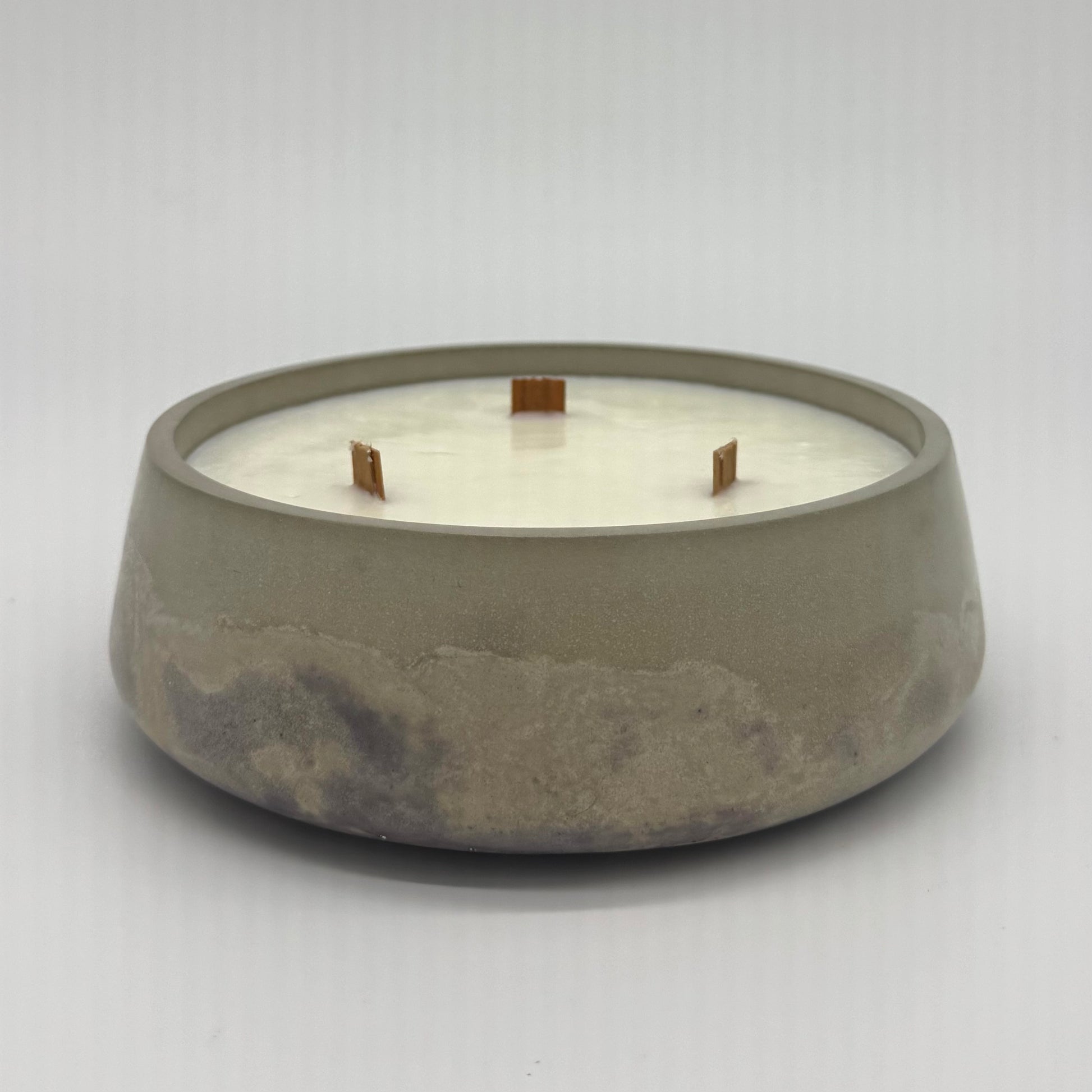 Concrete candle holder with a white candle inside on a light gray background