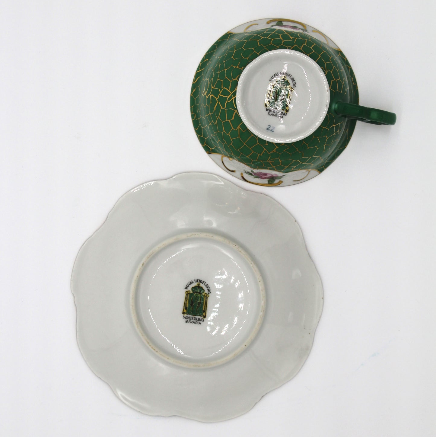 Ceramic cup and saucer with green and white design on a white background