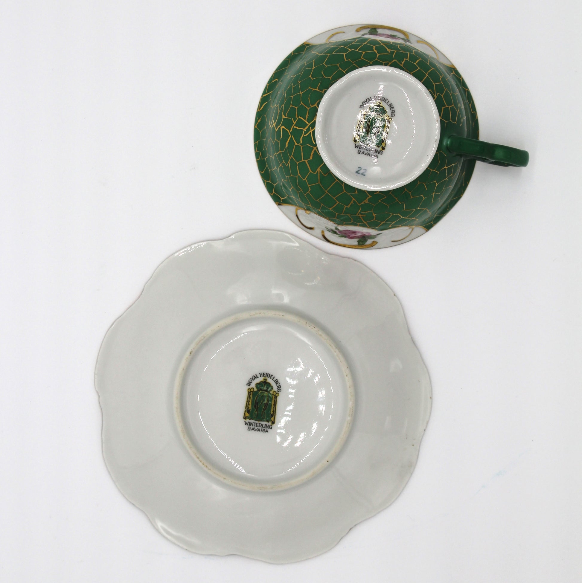 Ceramic cup and saucer with green and white design on a white background