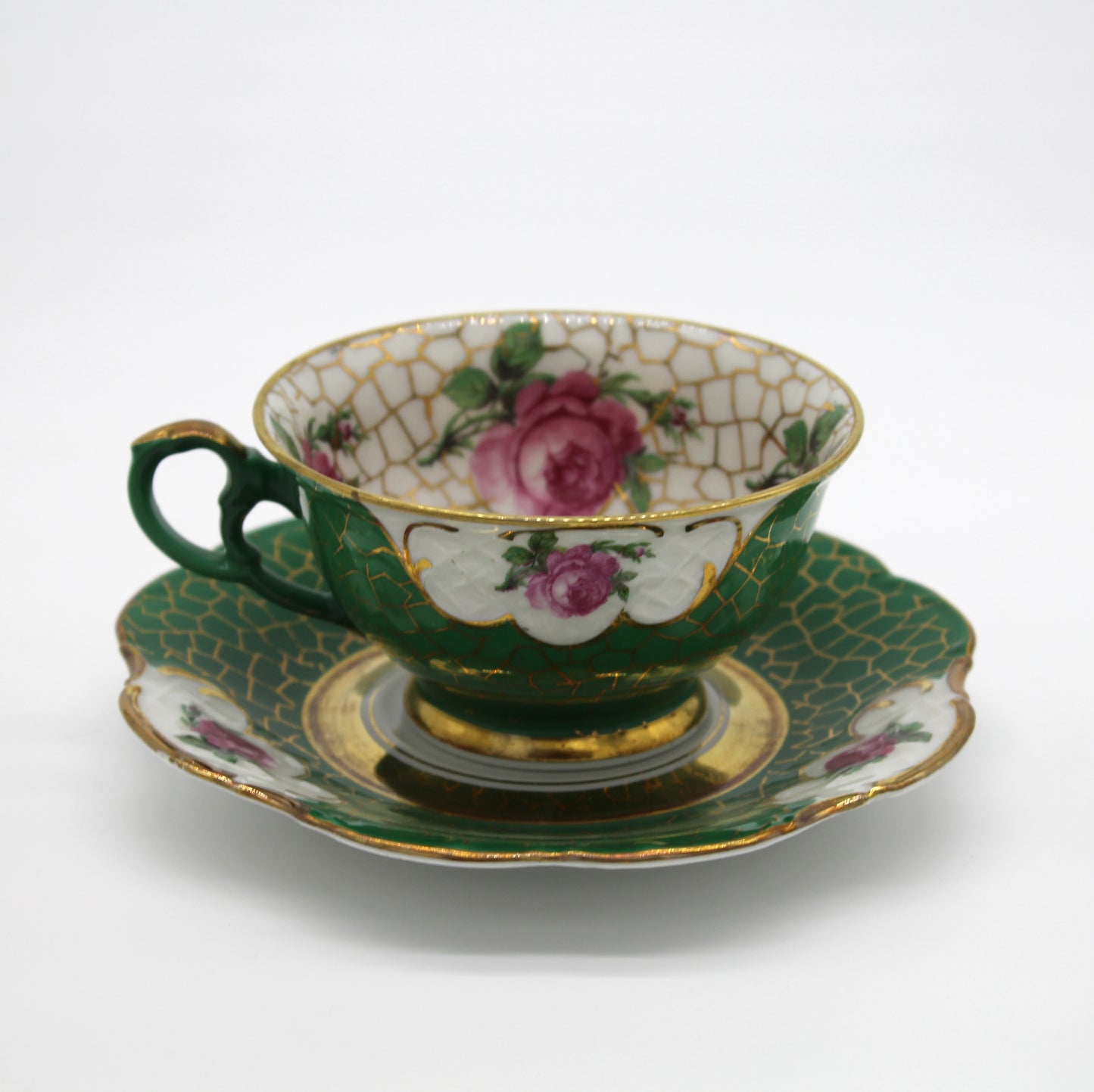 Decorative ceramic teacup and saucer with floral patterns on a white background