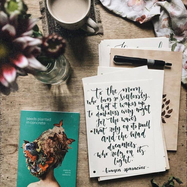 Tabletop scene with a book, stationery, and flowers on a wooden surface