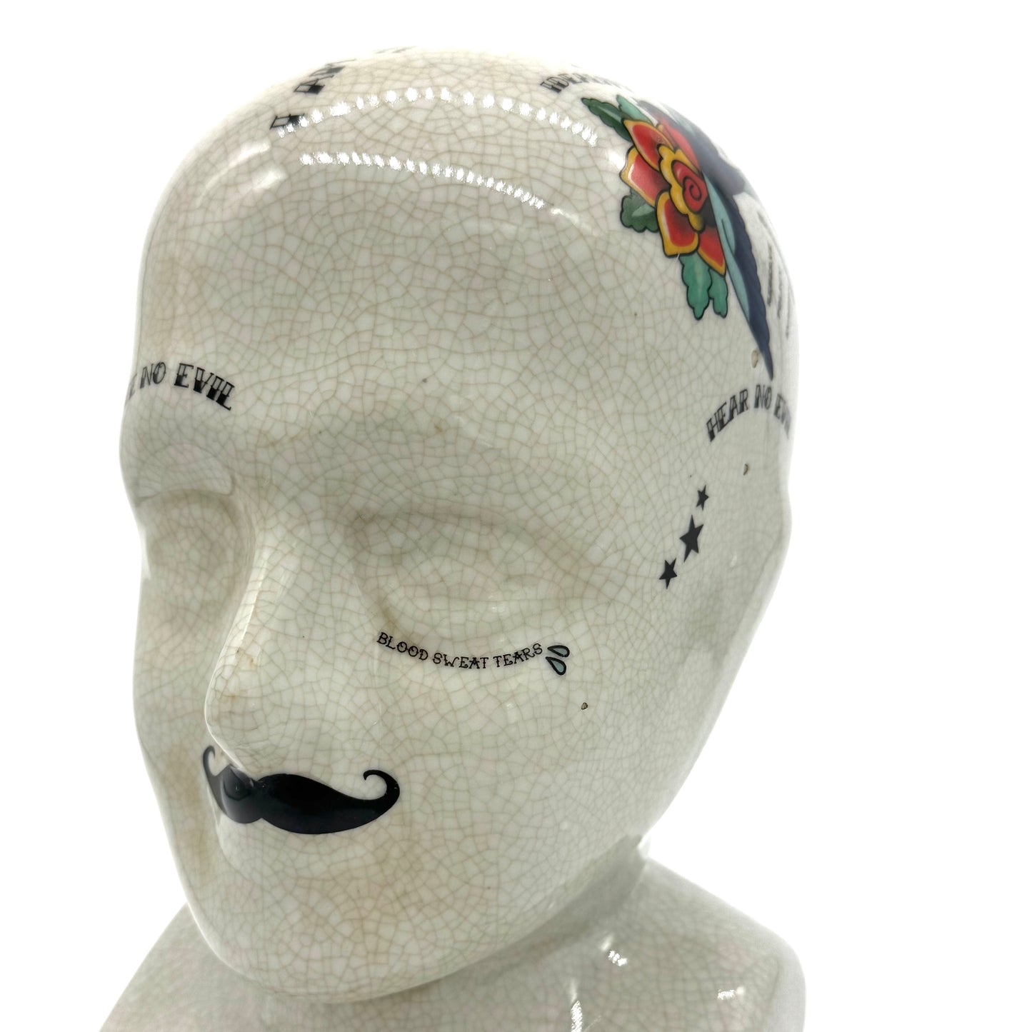Mannequin head with decorative tattoos and a mustache on a white background