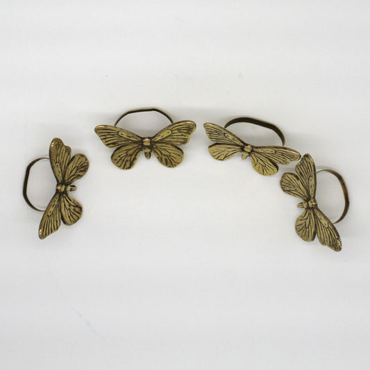 Set of four brass butterfly-shaped hair clips on a white background