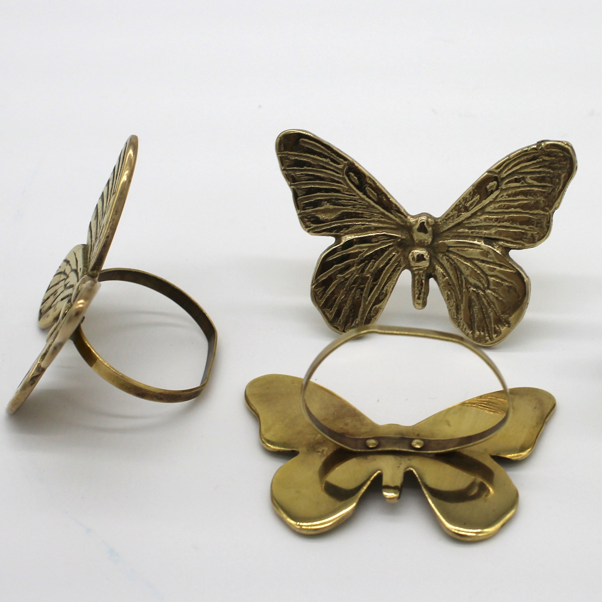 Three brass butterfly-shaped rings on a white background